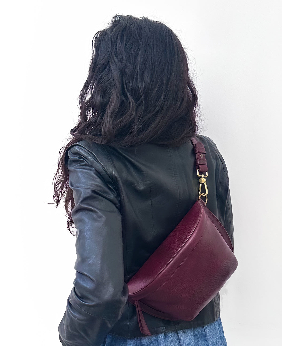 Mujer vistiendo la bandolera de piel genuina Bixi Awotan tono Red Wine cruzada en la espalda.   

Woman wearing the Bixi Awotan Red Wine genuine leather sling bag as a back crossbody. 