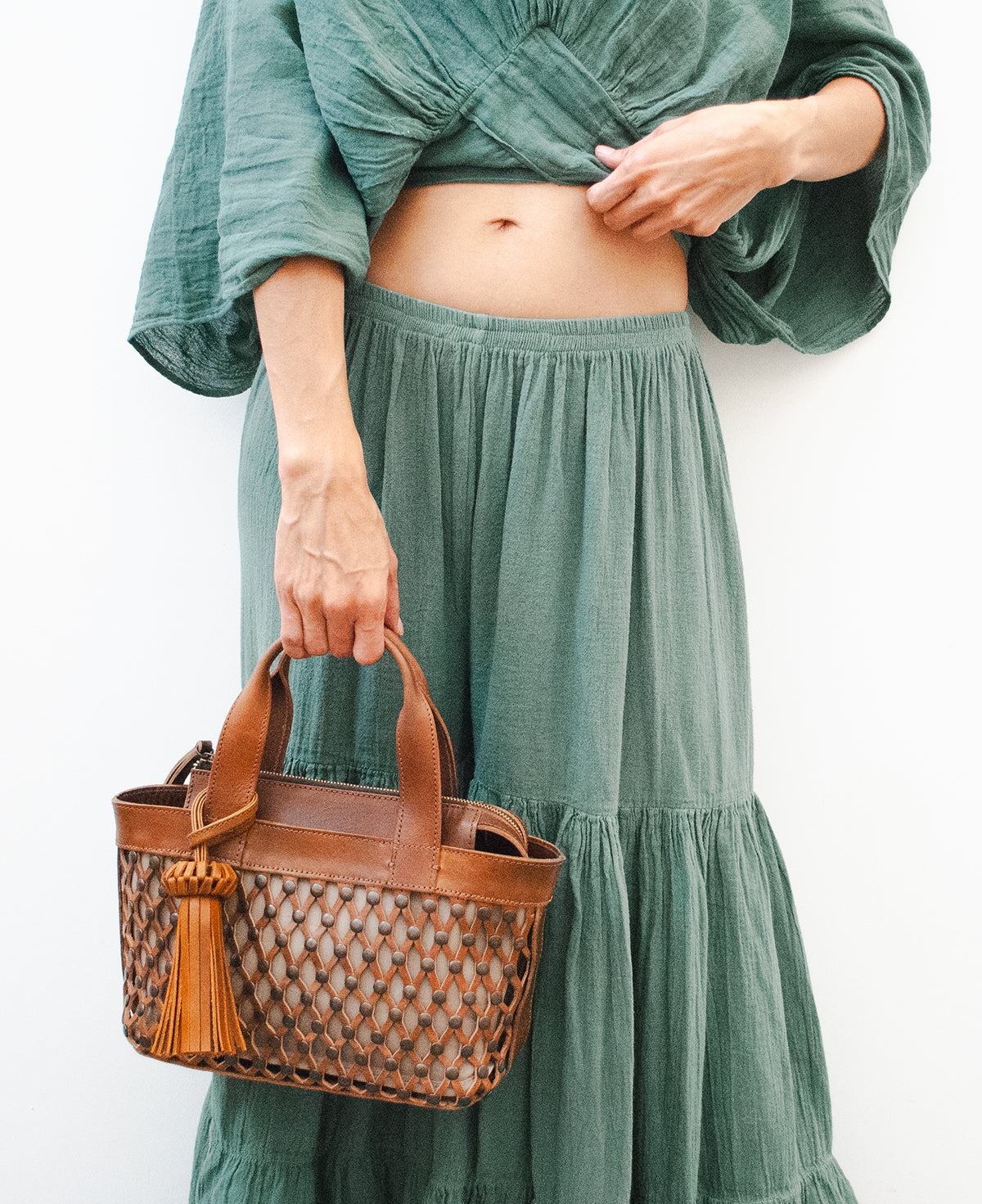 Close-up of premium caramel tan leather texture and silver metallic studs on a handcrafted bag.